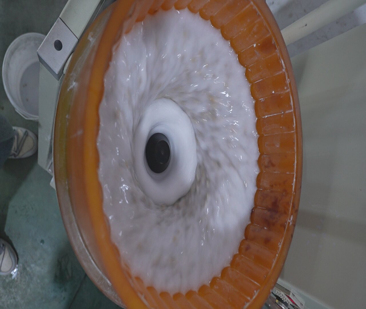 Intérieur d'une machine à cuve en fonctionnement : revêtement polyuréthane orange, eau et médias en écoulement toroïdal autour du moyeu central